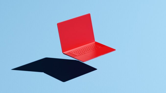 Conceptual image of a red laptop floating mid-air on a blue background with a hard shadow