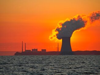 The sun rises behind a nuclear power plant cooling tower.
