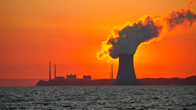 The sun rises behind a nuclear power plant cooling tower.
