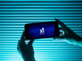 A person holds a telephone displaying the logo of Elon Musk s artificial intelligence grok in front of a background lit by a blue light.