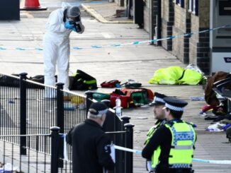 A forensic officer takes pictures in the cordoned-off area at Huntingdon Station
