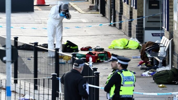 A forensic officer takes pictures in the cordoned-off area at Huntingdon Station