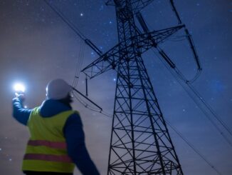 High-voltage engineer working on power lines at night.