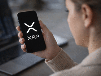 Person holding a smartphone displaying the XRP cryptocurrency logo while checking digital asset markets.