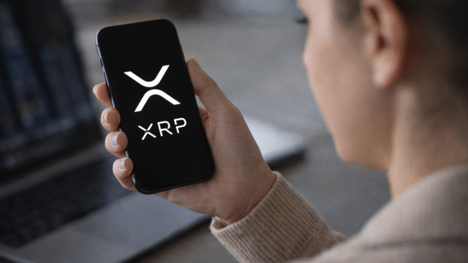 Person holding a smartphone displaying the XRP cryptocurrency logo while checking digital asset markets.