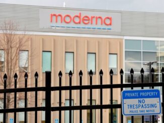 Image of a building with the Moderna logo behind a security fence.