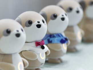 Four plastic anthropomorphic toy dogs are lined up on display at a trade show.