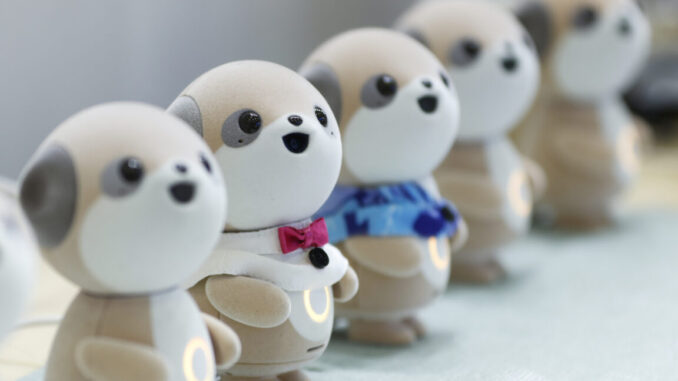 Four plastic anthropomorphic toy dogs are lined up on display at a trade show.