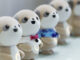 Four plastic anthropomorphic toy dogs are lined up on display at a trade show.